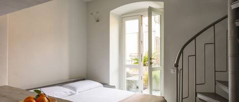 Ein Hotelzimmer mit einem Bett, einem Tisch mit Obst, einer Treppe und Blick ins Freie.
