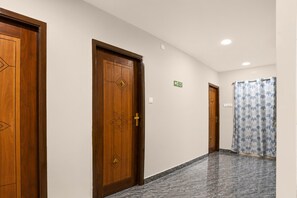 A hotel corridor with wooden doors, a shower area, and a marble floor. - Deluxe Room csn Grand Luxury Rooms (Nellore)
