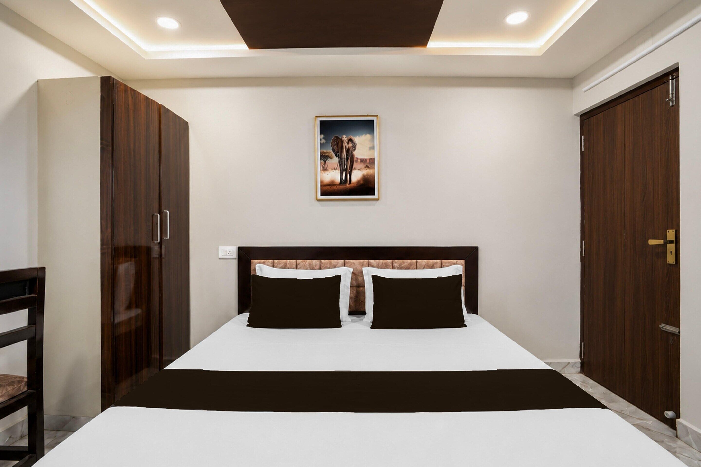 A bedroom with a bed, two nightstands, a headboard, a wardrobe, and a painting on the wall.