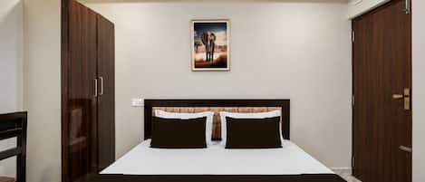 A bedroom with a bed, two nightstands, a headboard, a wardrobe, and a painting on the wall.