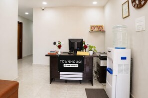 A reception desk labeled 'TOWNHOUSE' with a water dispenser, a computer, and a small plant. - Deluxe Room csn Grand Luxury Rooms (Nellore)