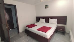 A bedroom with a bed, a nightstand, a ceiling fan, and a door. - Raya Raj Anugraha (Kumbakonam)