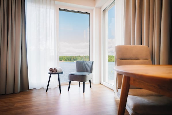 Quarto com vista para um lago, uma cadeira, uma mesinha e uma toalha enrolada em uma mesinha lateral.