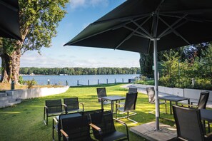 Un espacio de estar al aire libre con sillas y mesas, con vista a un lago.
