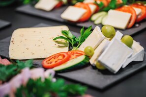 A variety of cheeses and fresh vegetables on a slate board. - H24 Hotel Berlin Grünau (Berlin)