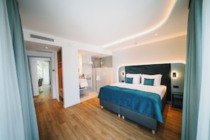A modern bedroom with a large bed, a walk-in closet, and a bathroom. - H24 Hotel Berlin Grünau (Berlin)