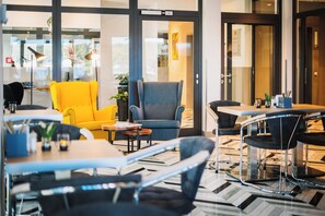 Un moderno vestíbulo de hotel con zonas de estar, una recepción y un amplio ventanal con vistas al interior.