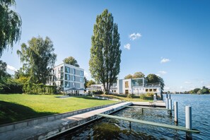 Un edificio moderno con piscina y muelle que se extiende sobre un lago.