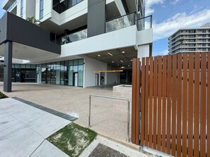 Un bâtiment moderne doté d’une façade en verre, d’une entrée sécurisée et surplombant un ciel dégagé.