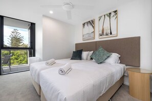 Ein modernes Hotelzimmer mit zwei Betten, einem großen Fenster und einem Balkon.