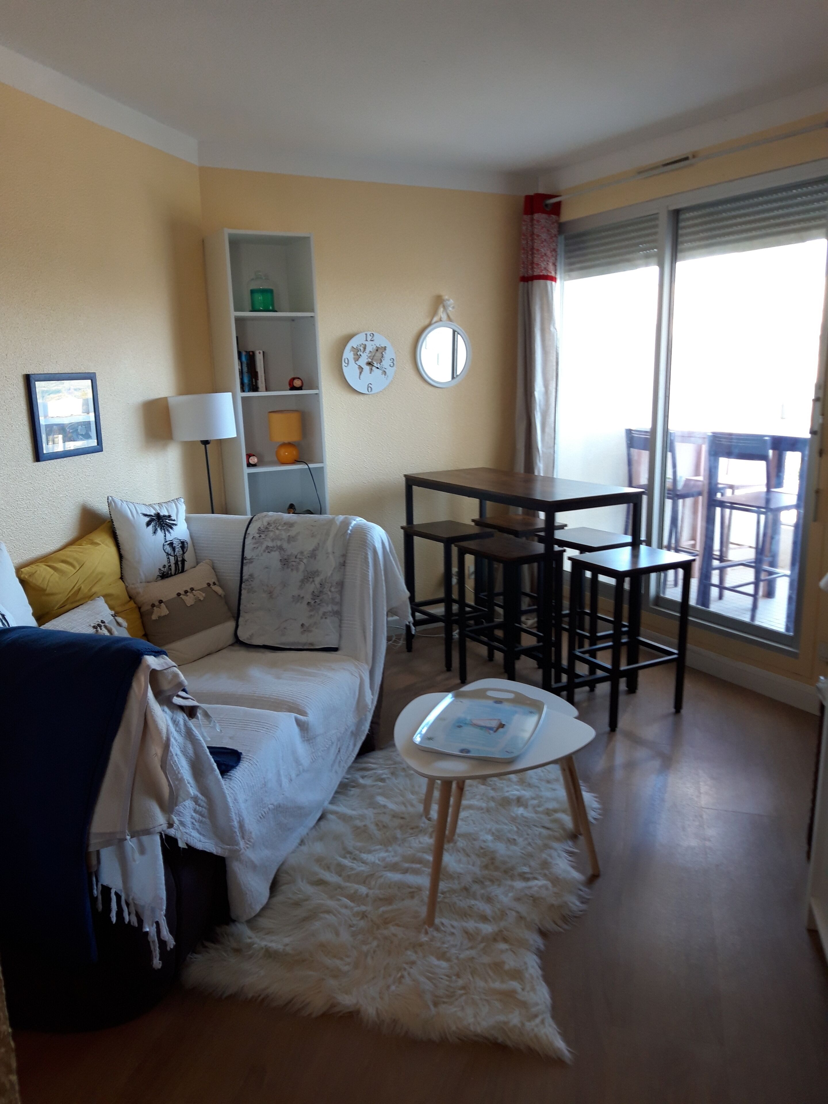 Un salon comprenant un canapé, une petite table, une bibliothèque et un coin repas avec des chaises.