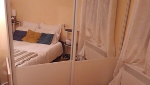 Makuuhuone, jossa on sänky, yöpöytä, peili ja verho.