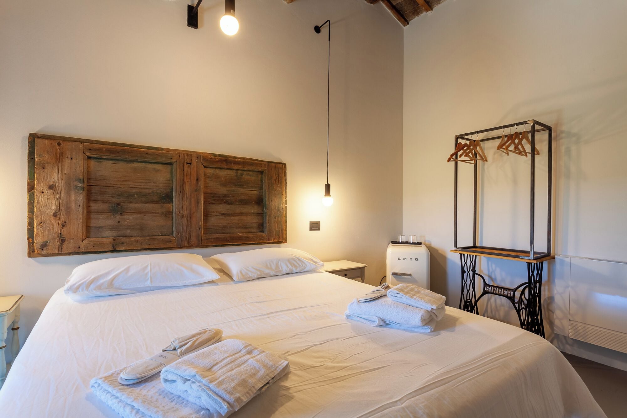 A hotel room with a large bed, a wooden headboard, a mirror, a radiator, and a small table.