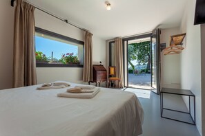 A hotel room with a bed, a desk, and a view of the outdoors.