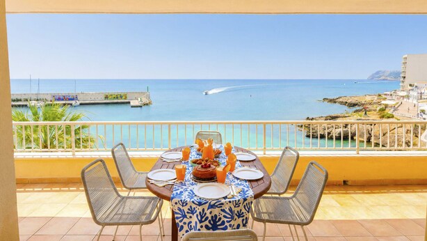 A dining table with chairs and a view of the sea. - Seafront Cala Ratjada Apartment (Cala Ratjada)