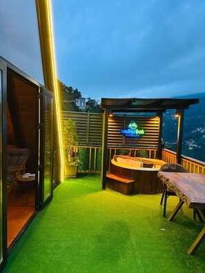 A rooftop bar with a neon sign, outdoor seating, and a view of the city.