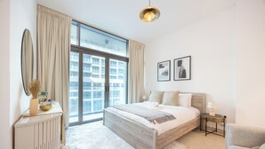 Ett modernt hotellrum med en stor säng, ett sidobord, en stol, ett stort fönster och utsikt över staden.
