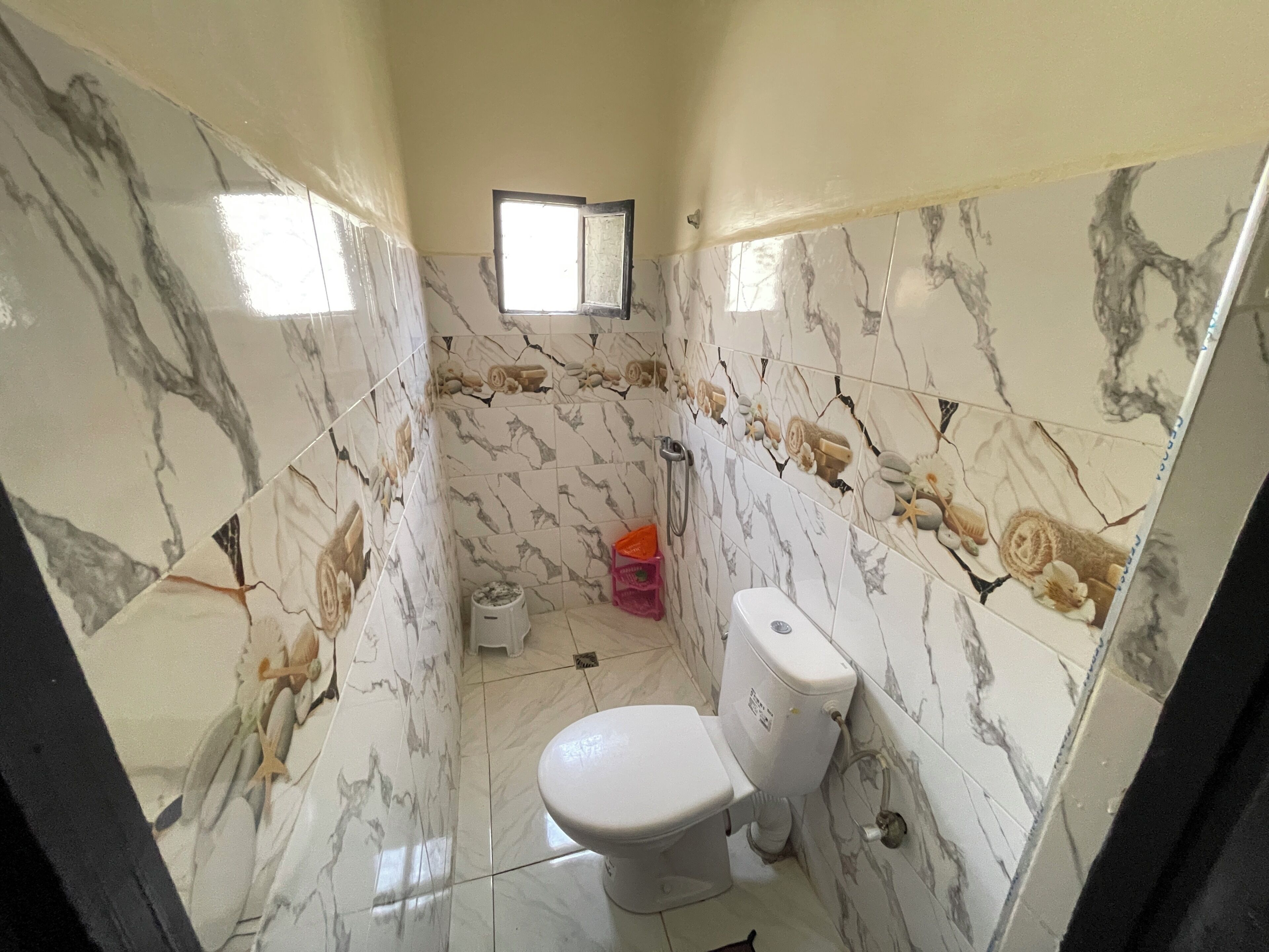 Un baño con inodoro, ducha y una ventana pequeña.