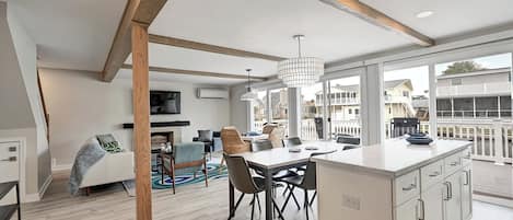 A modern kitchen with a large island, wooden beams, and a view of the ocean.