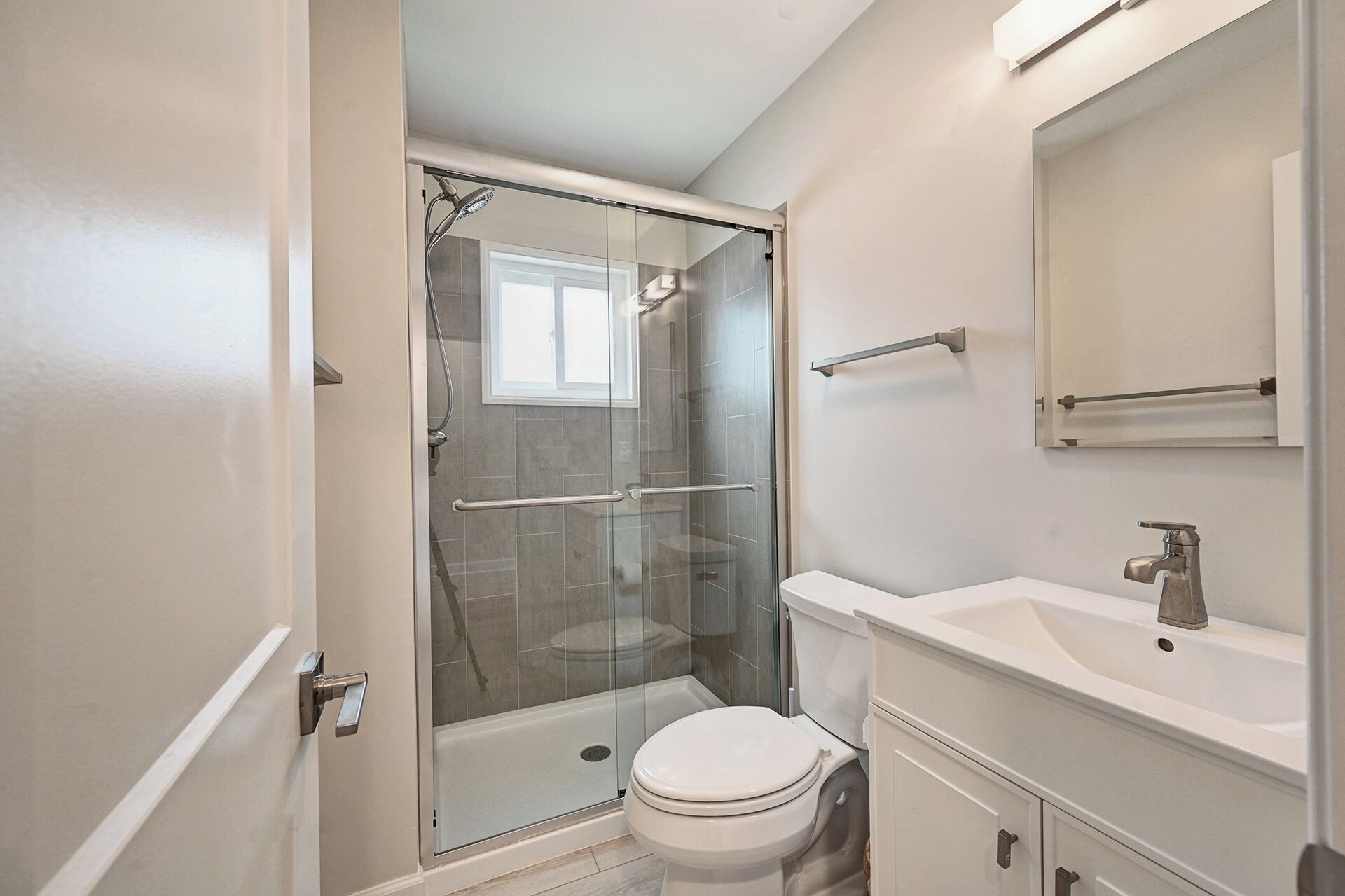 Un bany amb dutxa de vidre, un vàter i un lavabo amb mirall a la part superior.