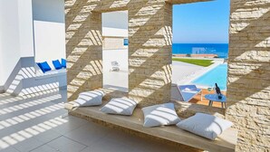 Une chambre moderne avec des murs en pierre, une vue sur la mer et un espace piscine.