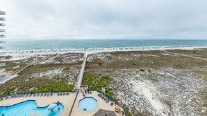Ein Strandresort mit Poolbereich, einem Promenadenweg und Blick auf den Strand.