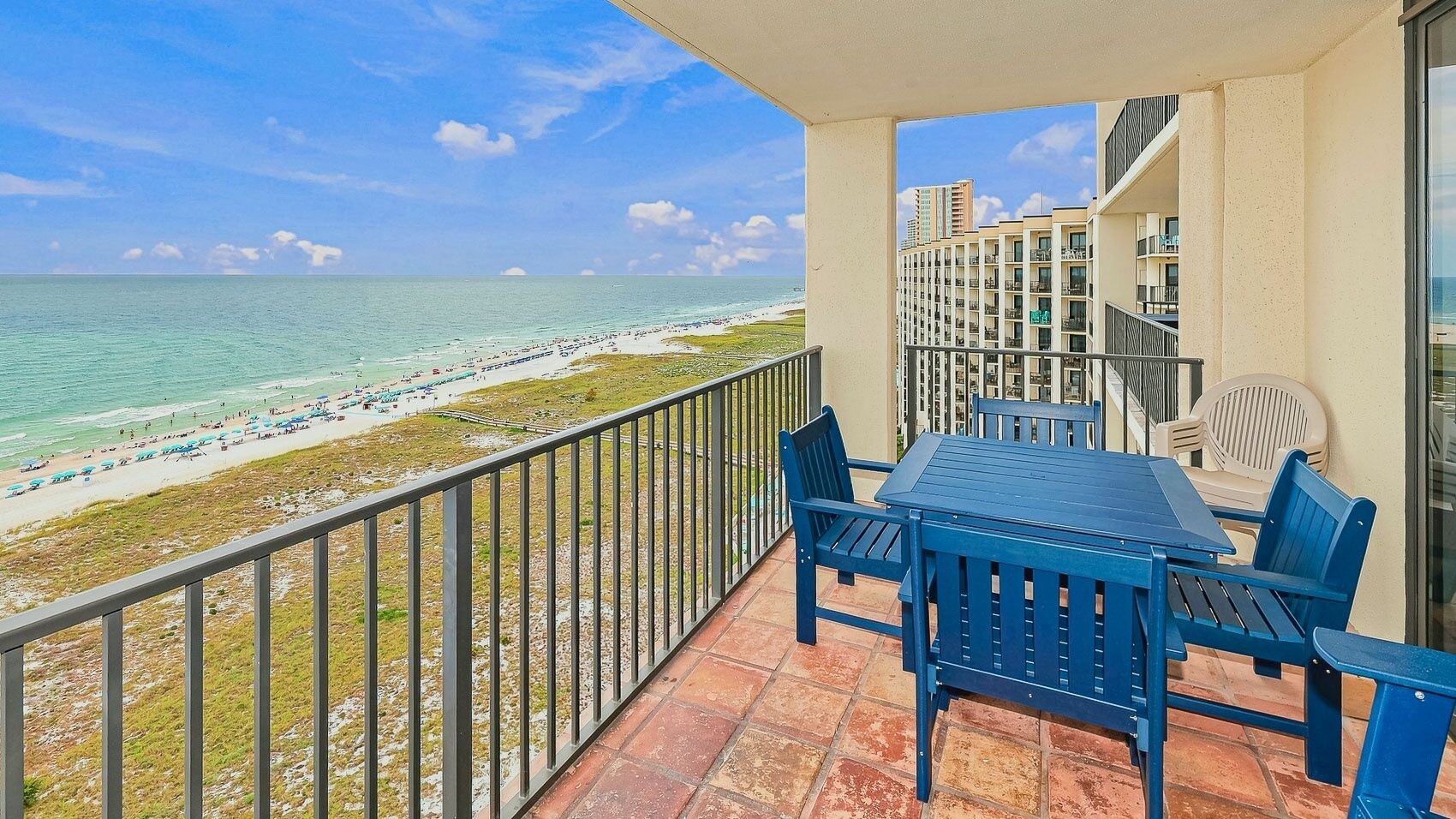 Een balkon met uitzicht op een strand en de oceaan, met een tafel en stoelen.