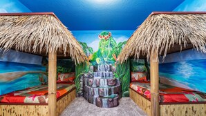 A room with a mural of a waterfall, two thatched-roof beds, and a central seating area. - 4312-Prologue (Kissimmee)