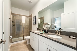 A modern bathroom with a glass-enclosed shower, two sinks, and a large mirror. - 4312-Prologue (Kissimmee)