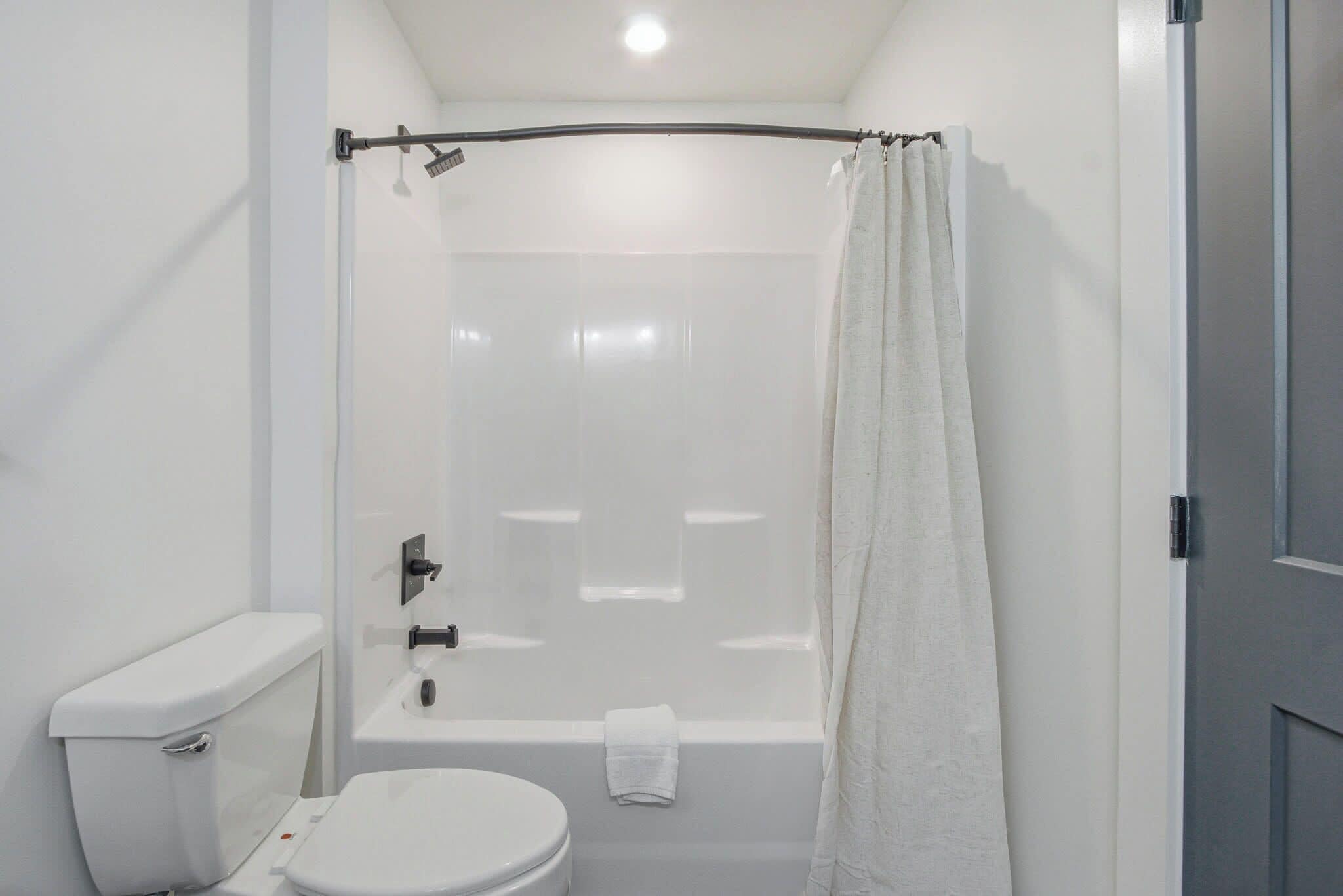 A bathroom with a toilet, a bathtub, and a shower curtain.