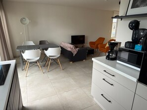 A modern living room with a dining table, chairs, a sofa, a TV, and a coffee machine. - 4P 2B Casa Riemst Luxurious Entertainer s Dream (Riemst)