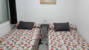 Une petite chambre propre, avec deux lits, une carte accrochée au mur et un appareil de climatisation.