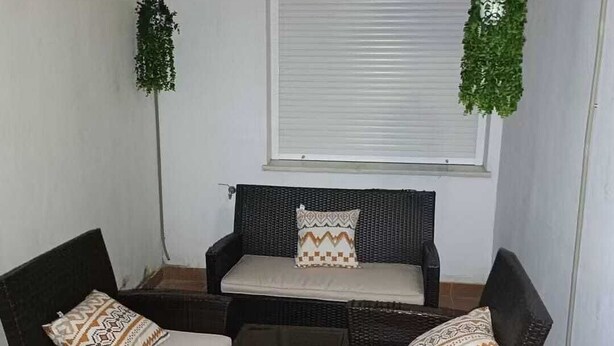 Un petit espace extérieur aménagé avec des meubles en osier, une table et un ventilateur de plafond.