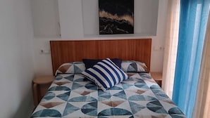 Un lit avec une couvre-lit à motifs géométriques, une tête de lit en bois et un seul oreiller.
