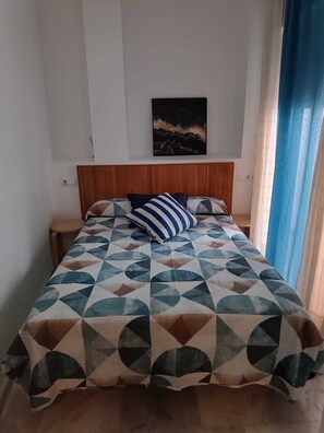 Ein Bett mit einem geometrisch gemusterten Überwurf, einem Holzkopfstück und einem Kissen.