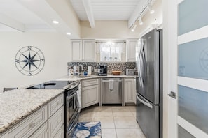 A kitchen with white cabinets, a stainless steel refrigerator, a microwave, and a stove. - 2BR | Sunsets, Two Balconies, Steps to Beach (Indian Shores)