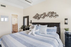Une chambre à coucher comprenant un lit, une sculpture de poisson fixée au mur, un miroir et une table de chevet avec une plante.