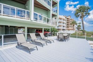 Une propriété située en bord de mer, dotée d’une terrasse couverte, de meubles d’extérieur et offrant une vue sur l’océan.