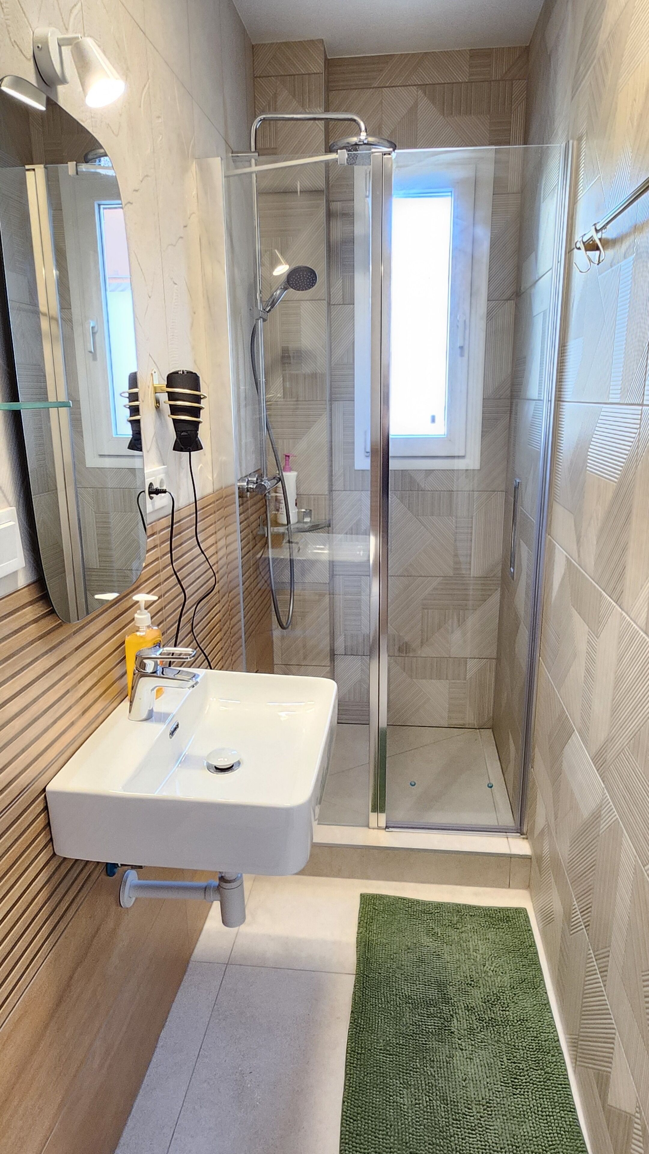 Un bagno moderno con doccia in vetro, un lavandino bianco e un tappeto verde.