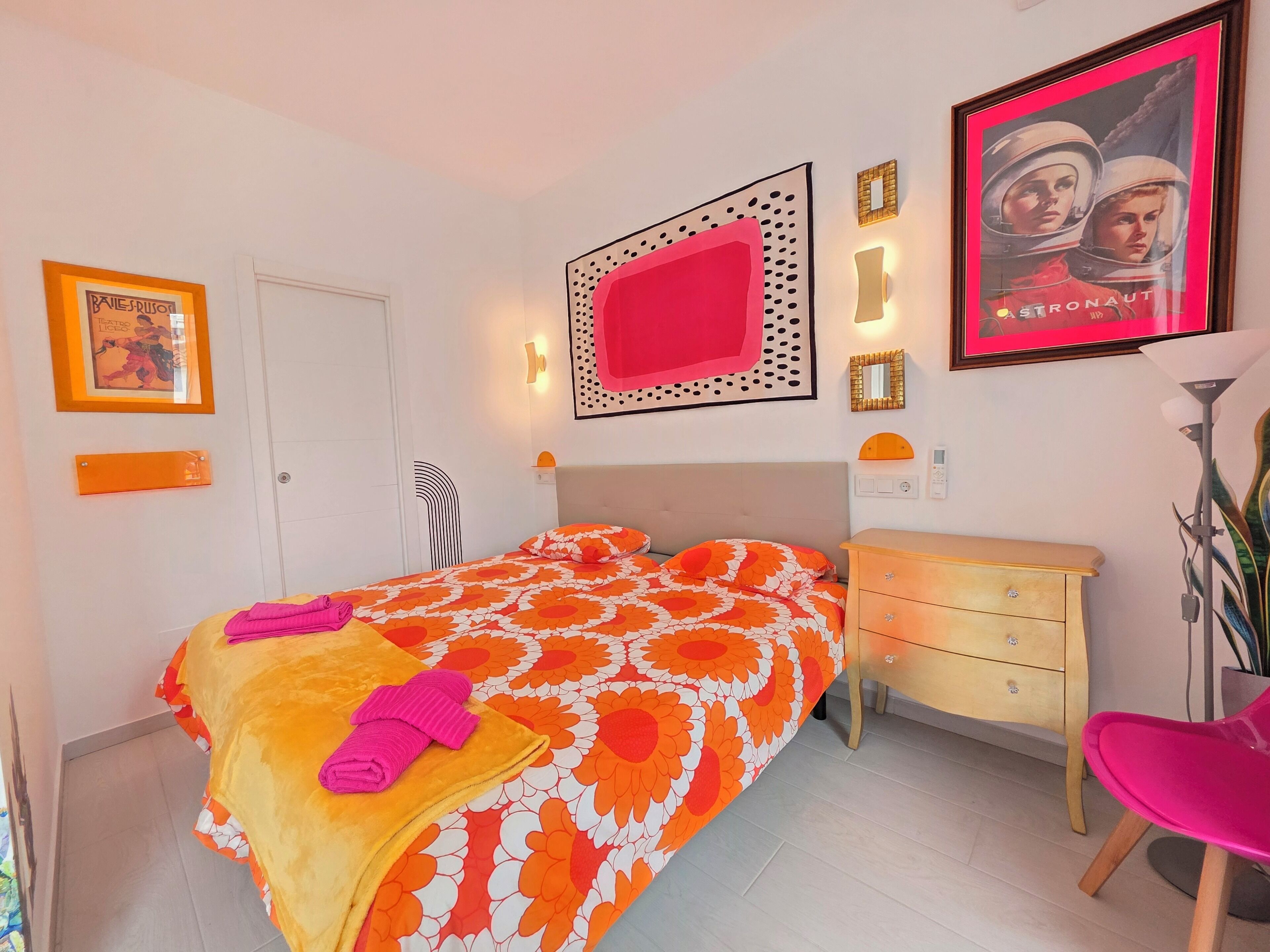 Ein Schlafzimmer mit einem Bett, einem Schminktisch, einem Stuhl und einem Poster an der Wand.