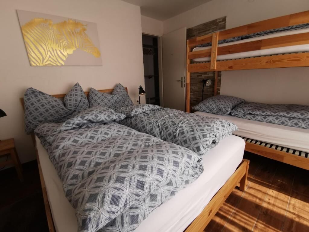 A room with two bunk beds, patterned bedding, a zebra print artwork, and a wooden floor.