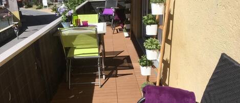 A balcony with outdoor furniture, potted plants, and a view of the surrounding area.