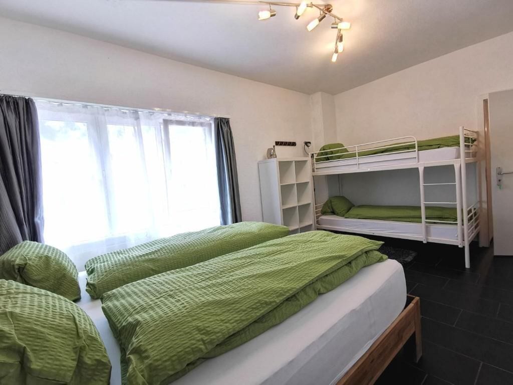 A room with bunk beds, a desk, and a window with curtains.