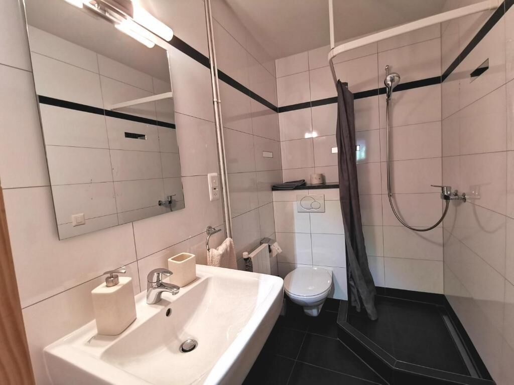 Een moderne badkamer met wastafel, toilet en douche.