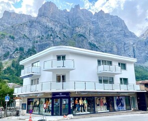 Um edifício branco com vitrine e manequins, com montanhas ao fundo.