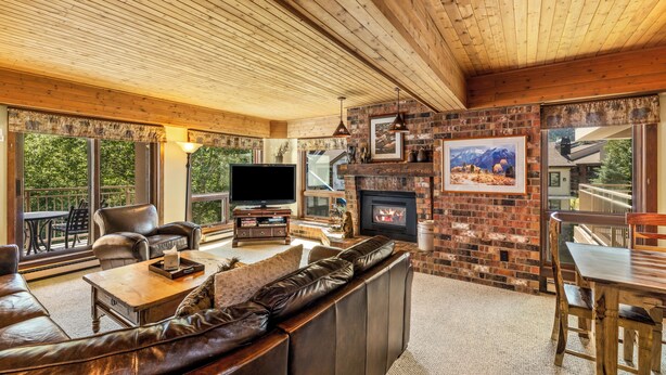 A cozy living room with a fireplace, leather sofa, and a television. - Slope-Side Retreat at the Steamboat Resort Base Area (Steamboat Springs)