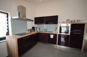 A compact kitchen with dark cabinets, a stainless steel oven, and a window with a lace curtain. - CASA Gabrijela - Attic apartment with a very large balcony (Poreč)