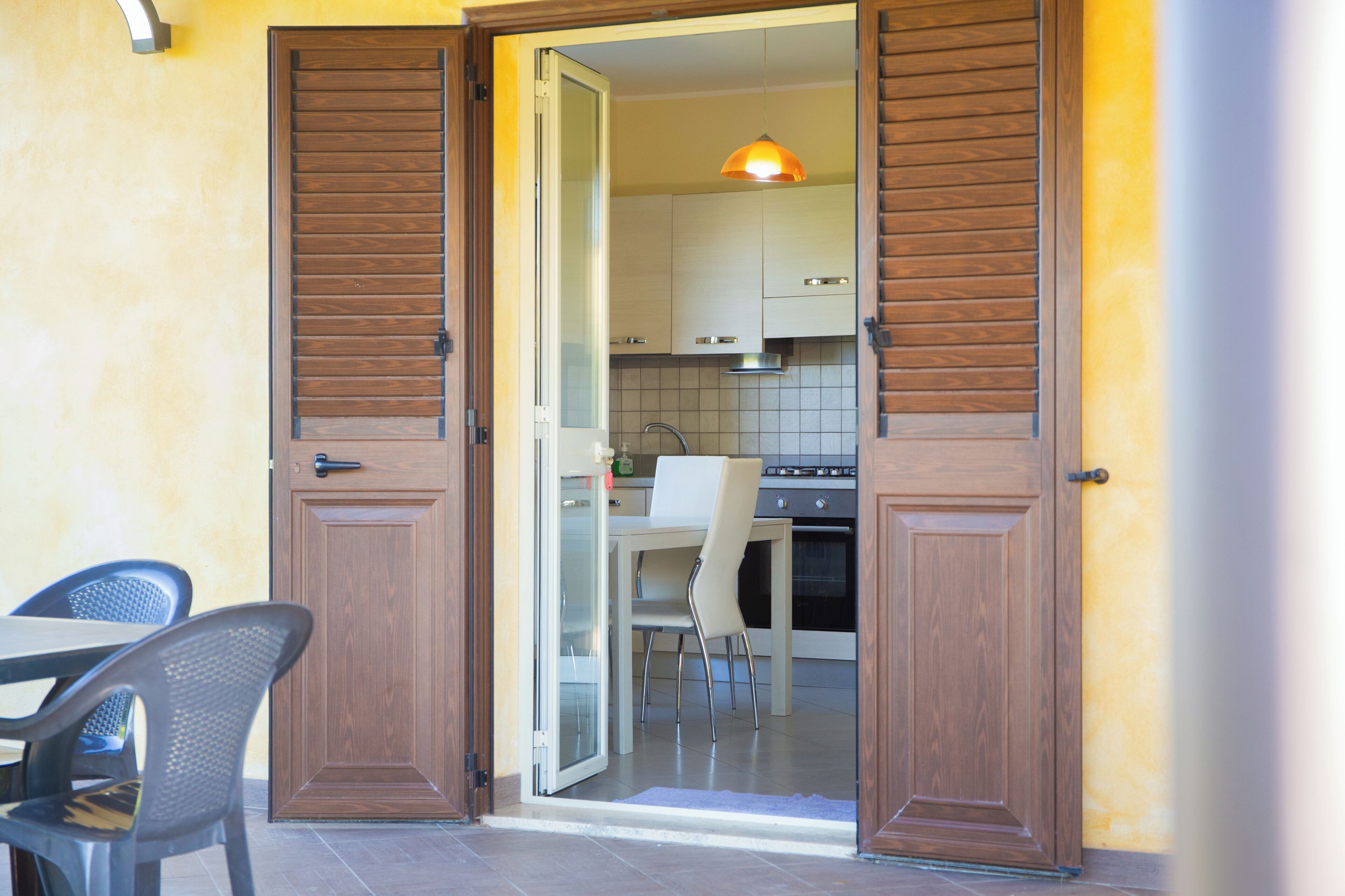 Puerta abierta a una cocina con una mesa de comedor y sillas, un lámpara colgante y un salpicadero de azulejos.