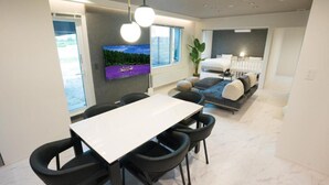Um interior moderno com área de jantar, sofá e televisão fixada na parede.