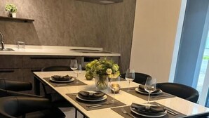 A modern dining area with a long table, black chairs, and a vase of flowers. - Private Villa Yuki no oto (Furano-shi)